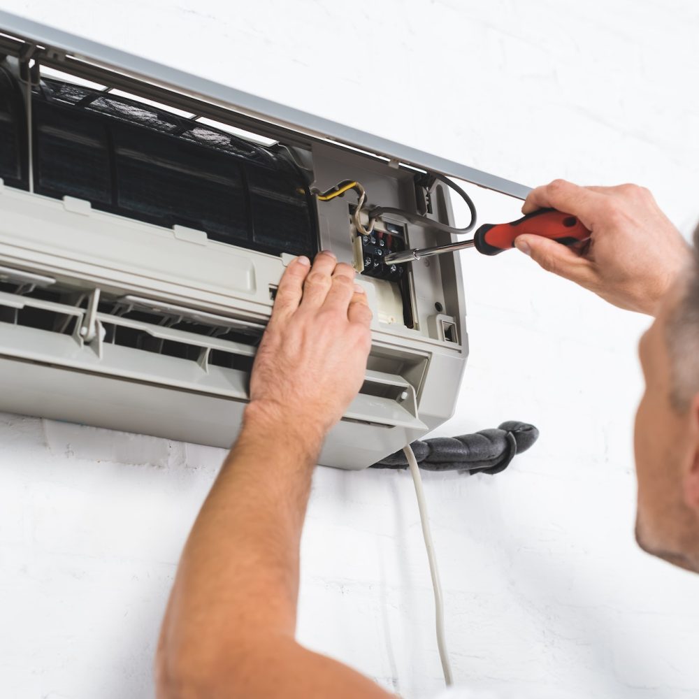 close up view of adult repairman repairing air conditioner